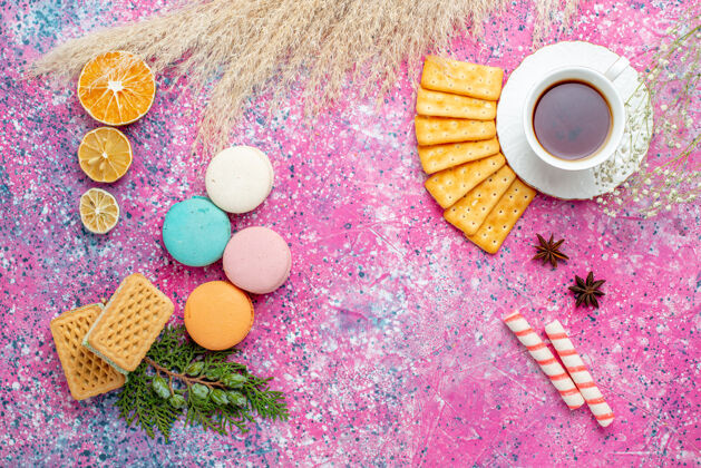 护理浅粉色的桌子上放着一杯茶 上面放着饼干和法式马卡龙法式水疗脆的