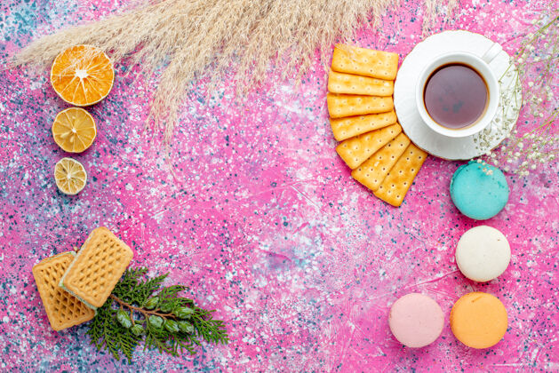 饮料在粉红色的桌子上可以俯瞰一杯茶 里面有饼干 法式马卡龙和华夫饼食物华夫饼生的