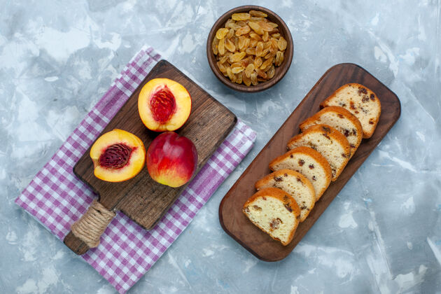 美味顶视图新鲜桃子醇厚可口的水果蛋糕和葡萄干在浅白色的桌子上顶部肉盘子