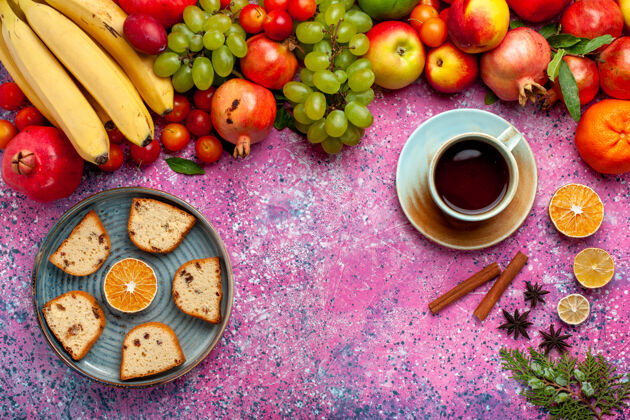 蛋糕顶视图新鲜水果组成五颜六色的水果与美味的切片蛋糕和茶在粉红色的桌子上食物派桌子