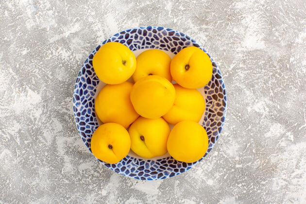 顶部顶视图新鲜甜杏黄色水果盘内白色表面柠檬多汁可食用的水果