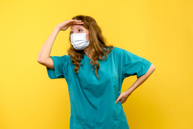 年轻女医生黄色空间里戴着面具的年轻女医生冠状病毒人视图