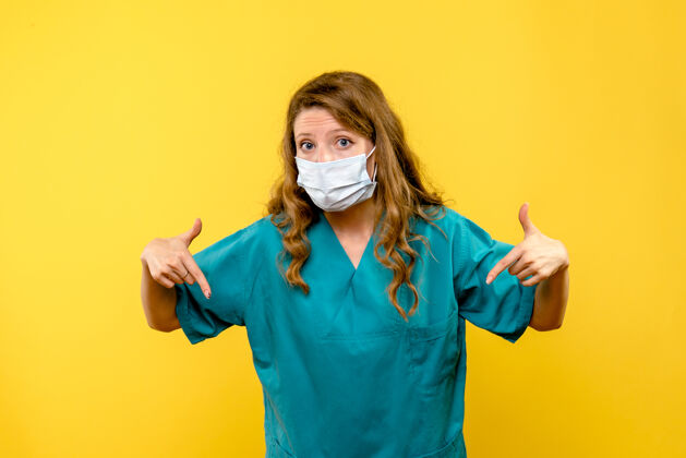 漂亮正面图黄色地板上戴着面罩的女医生医护人员-大流行黑发视图冠状病毒