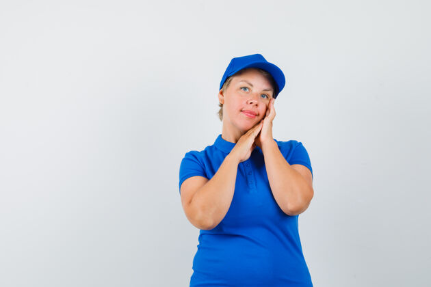 女性一个成熟的女人穿着蓝色t恤检查她的面部皮肤 看起来很优雅帽子肖像自信