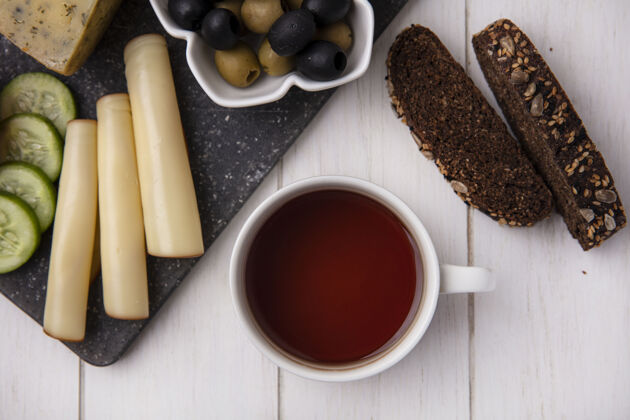 茶顶视图：一杯茶 配烟熏奶酪 橄榄和白底黑面包片切片顶红