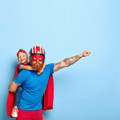 超级英雄强大的爸爸把小猪还给孩子 展示勇气 做飞翔的手势 戴头盔 戴红色面具父母身份父亲身份面具