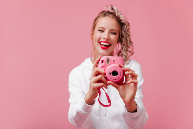 卷发微笑的女摄影师在粉红色的墙上工作肖像微笑美女