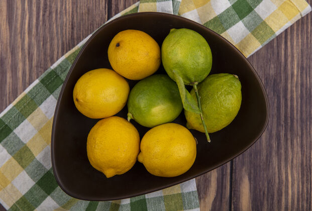 水果顶视图柠檬与酸橙在一个黄绿色格子毛巾在一个木背景碗柑橘酸橙碗