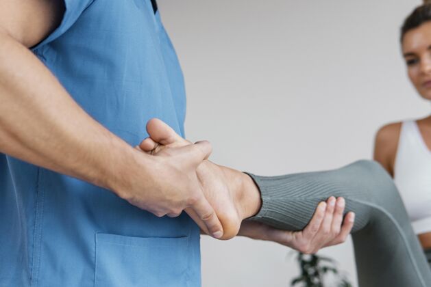 水平男性骨科治疗师低角度检查女性患者的腿部运动非侵入性骨病治疗