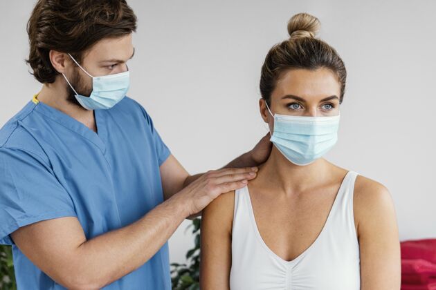 治疗师男性骨科治疗师带着医用面罩检查女性患者的颈部医生骨病健康