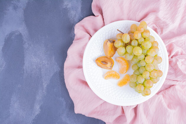 新鲜白盘子里的葡萄和枣李异国情调一串季节