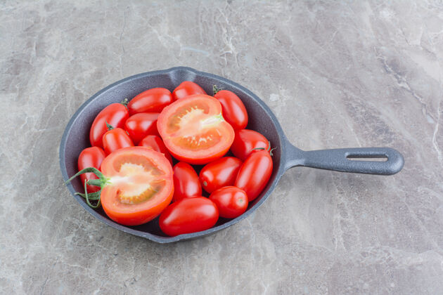 水果在一个黑色的平底锅里放一个红色的全切和半切的樱桃番茄可口蔬菜健康