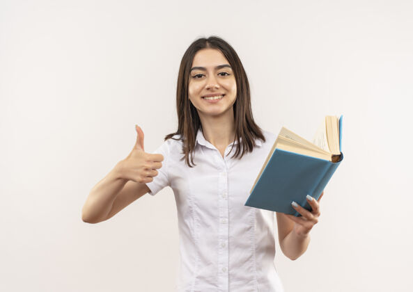 衬衫穿着白衬衫的年轻女孩拿着书望着前面 竖起大拇指站在白墙上看人书