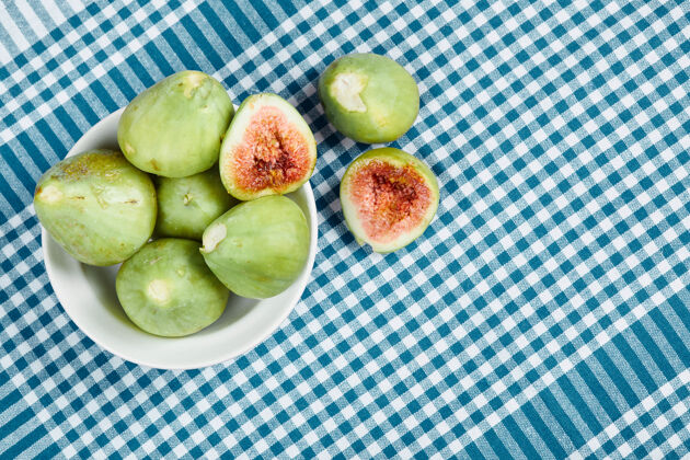 热带绿色的无花果在白色的碗里 在蓝色的桌布上成熟的盘子食物