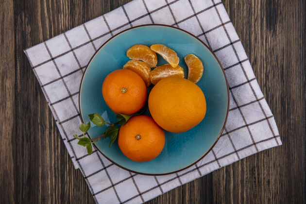 毛巾顶视图橘子与剥皮楔在一个蓝色的盘子上的方格毛巾彩色果皮视图