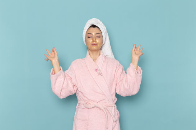 人正面图年轻女性穿着粉色浴袍淋浴后在蓝色墙上清洗美容洁面水自护霜淋浴肖像微笑年轻人