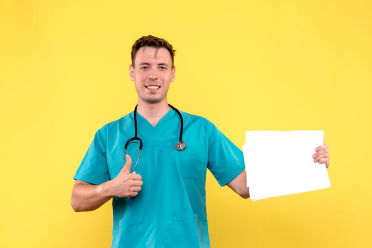 健康黄色墙上拿着文件的男医生的正视图药医院护士