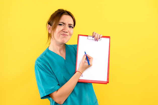 文件黄色墙上拿着钢笔和文件的女兽医的正面图人持有微笑