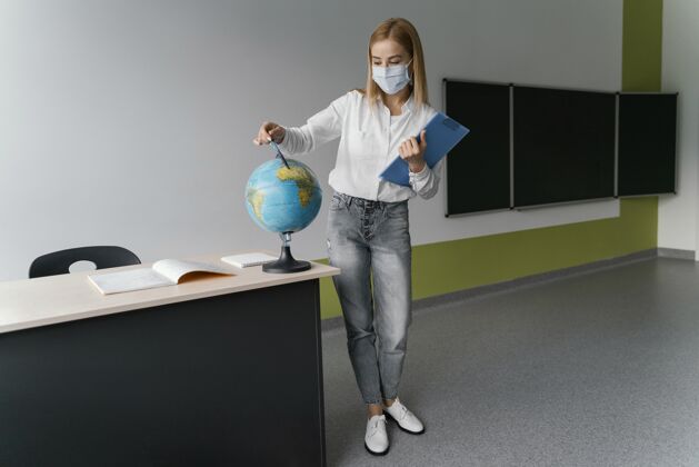 病毒教室里拿着剪贴板指着地球仪的女老师女性教师学习