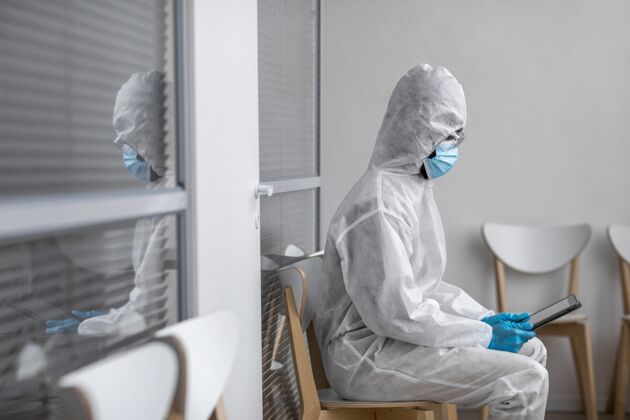 病毒穿防护服的人看着平板电脑设备防护服面罩