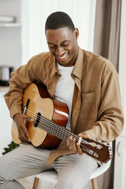 娱乐笑脸男音乐家在家弹吉他技能房子乐器
