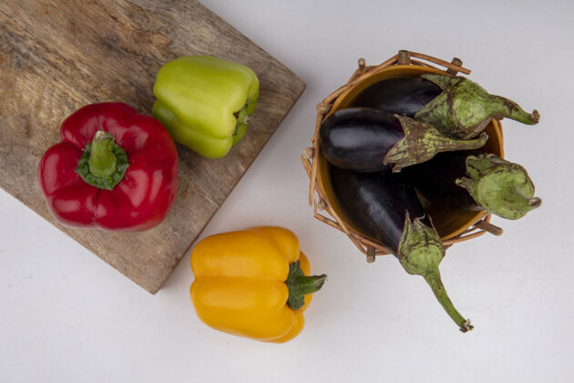 胡椒顶视图黑色茄子放在篮子里 菜板上放着彩色的甜椒顶部铃铛烹饪