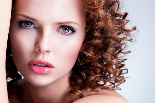 魅力美丽的黑发年轻女子的肖像 明亮的妆容卷发的特写脸姿势口红触摸
