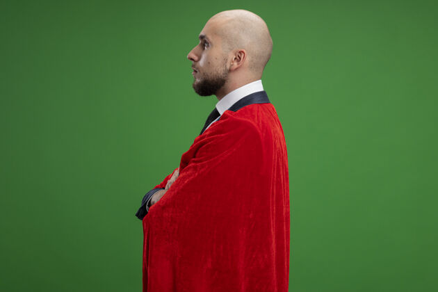 超级超级英雄 留着胡子 披着红斗篷的商人 脸严肃地站在绿墙上男人脸超级英雄