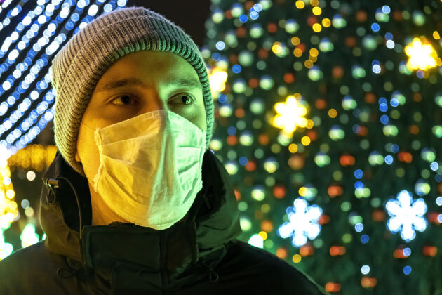 道路在摩尔多瓦的基希讷乌 一个戴着防毒面具 穿着冬衣的男人在夜晚 背景上是圣诞装饰保护户外英俊
