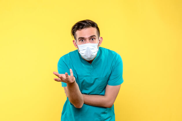 男医生黄墙上戴着无菌口罩的男医生的正视图人男人衬衫
