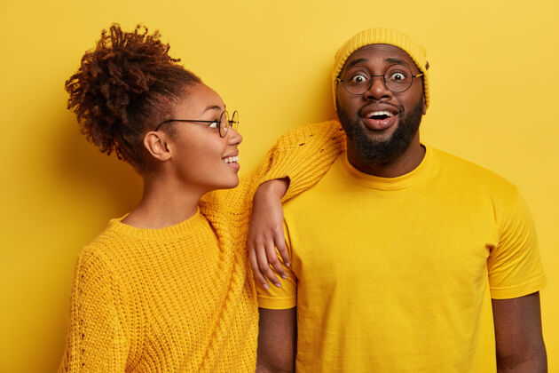 帽子两个穿着黄色衣服的黑人朋友 有着快乐的表情 非洲裔美国女人靠在胡子男人的肩膀上幸运满意女