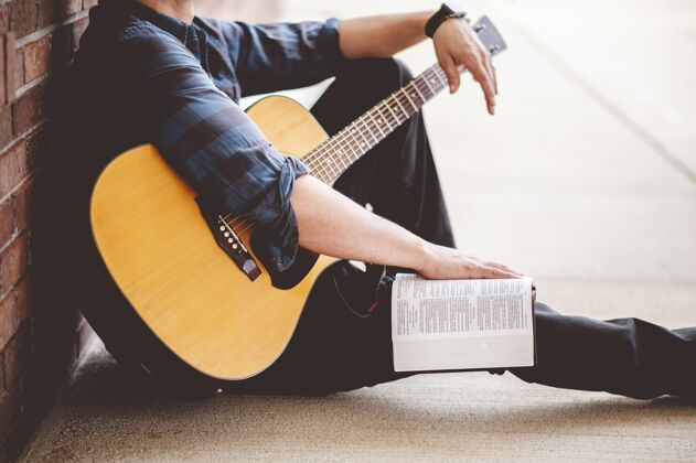 吉他特写镜头一个年轻的男性坐在手里拿着一本书和一把吉他白书艺术家