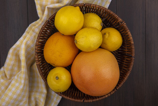 格子顶视图柠檬与橙色和葡萄柚在篮子与黄色方格毛巾木制背景葡萄柚食物橘子