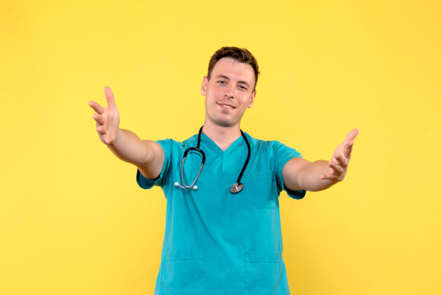情绪黄色墙壁上的男医生的正面图 带着喜悦的表情微笑听诊器专业