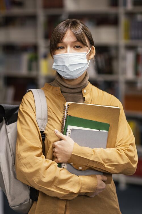 妇女戴着医用口罩的学生在图书馆社区面罩年轻