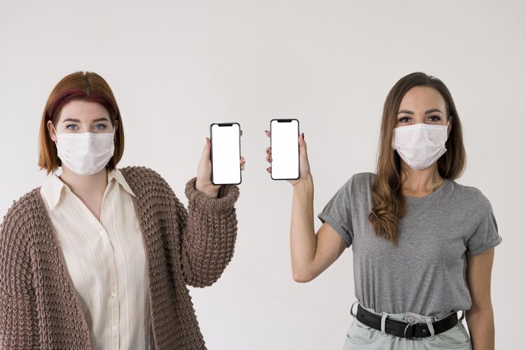 安全戴着口罩手持智能手机的女性正面图预防防护移动