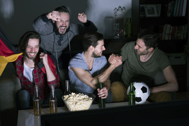 电视一群男人在电视上喝啤酒看足球零食支持兴奋