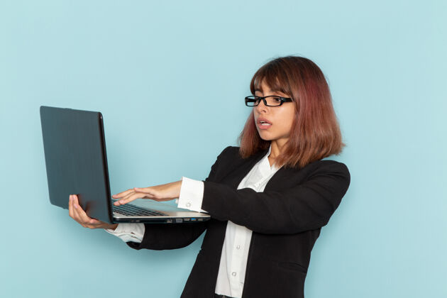工作正面图：穿着西装的女上班族在浅蓝色的表面上使用笔记本电脑笔记本电脑笔记本电脑前台