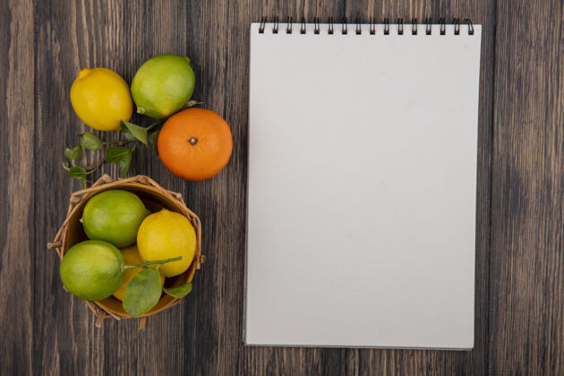 视图顶视图复制空间记事本与橙色柠檬和酸橙在一个木制背景篮子笔记本记事本顶部