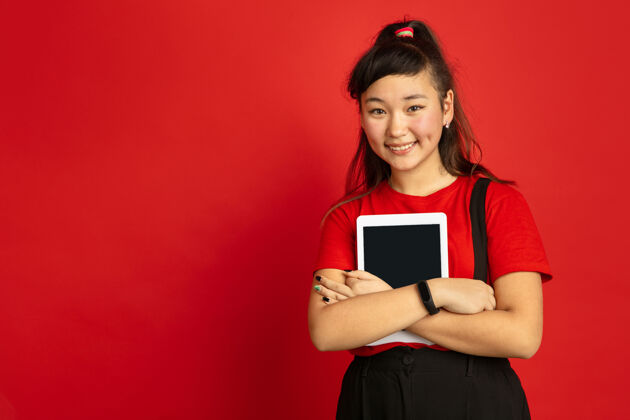 表达亚洲青少年的肖像画被隔离在红色工作室的背景上美丽的深褐色女性模特 留着休闲的长发人类情感的概念 面部表情 销售 广告手持平板电脑Vlog梯度公司