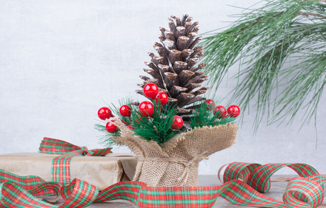圆锥体巨大的节日圣诞松果 大理石背景上有礼物和蝴蝶结松树礼物松果
