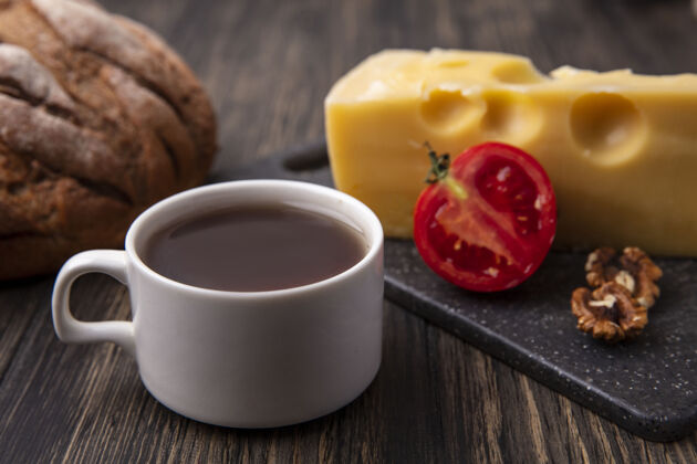 架子侧视图：一杯茶 上面放着马斯坦奶酪和西红柿 桌上放着黑面包红茶西红柿茶