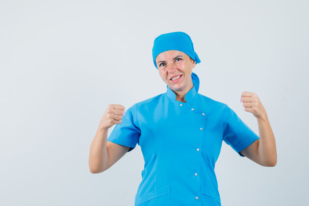 手势女医生穿着蓝色制服 展示获奖者的姿态 看上去很幸运正视图实验室治疗制服