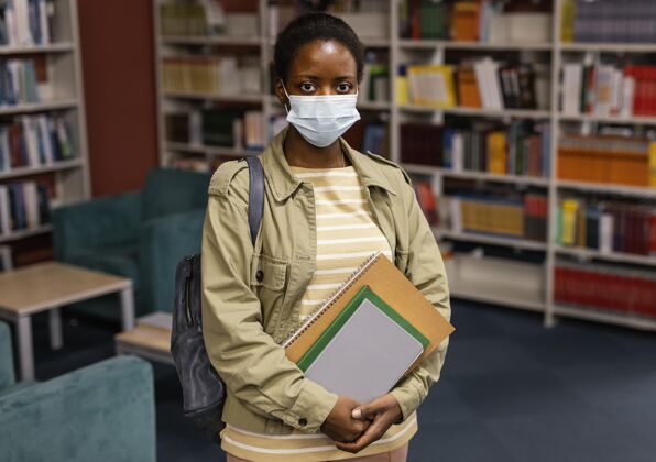 年轻戴着口罩的学生在图书馆大学生活方式Campus学生