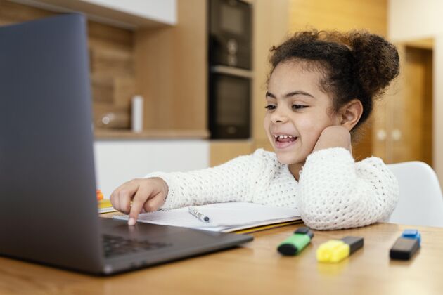 网络笑眯眯的小女孩在家上网上学时带着笔记本电脑学习课程女孩