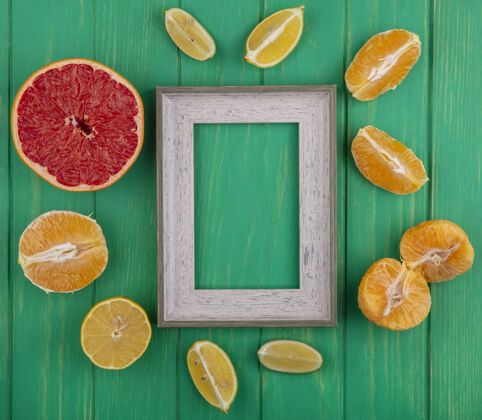 顶部顶视图复制空间灰色框架与去皮橙子和柠檬酸橙和半葡萄柚片绿色背景果皮一半绿色