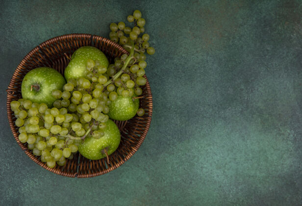视图顶视图复制空间绿色背景上篮子里的绿色葡萄和苹果篮子食物水果