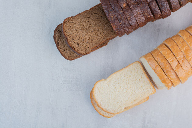 美味新鲜的白色和棕色面包片放在大理石背景上切片棕色糕点