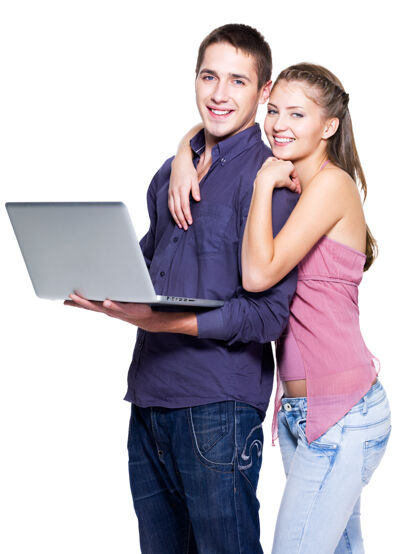 高兴在白墙上挂着笔记本电脑的快乐年轻夫妇在线笔记本肖像