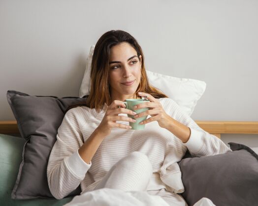 度假在床上喝咖啡的女人的前视图逗留住宿房子